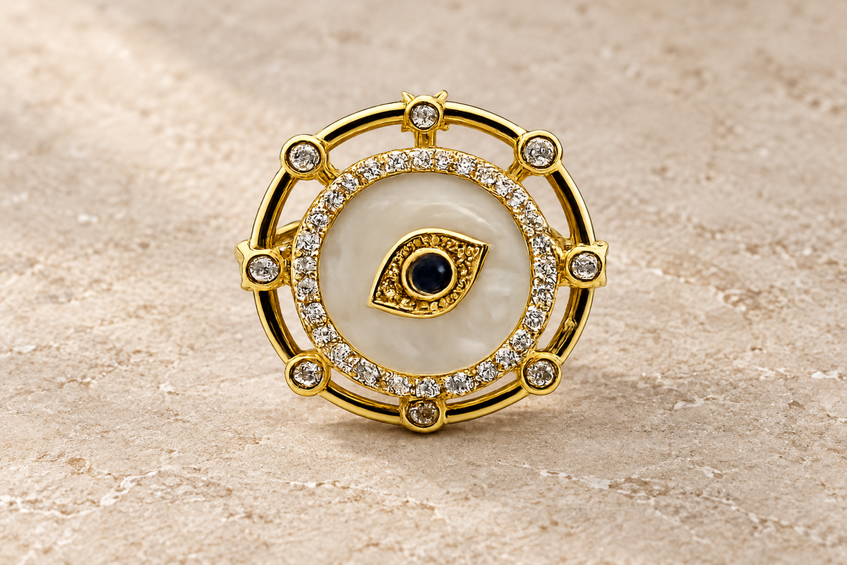 The Celestial Eye Ring with a pearlescent disk, central dark eye and gold crystal frame.
